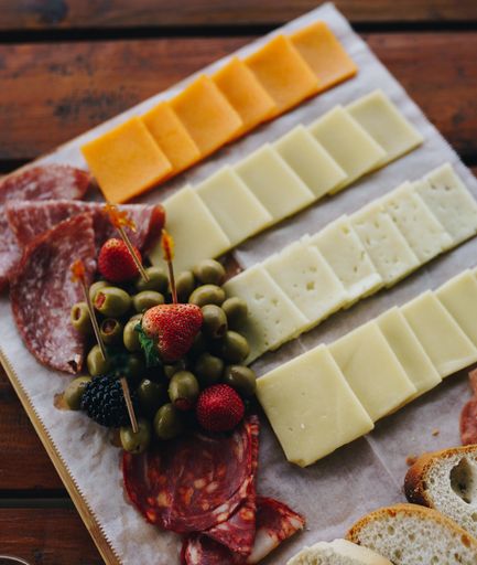 A vertical high angle shot of different types of cheese and meat on a plate