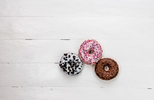 The colorful glazed donuts with sprinkles on wooden table