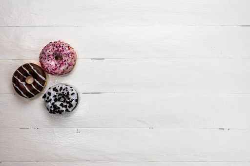 The colorful glazed donuts with sprinkles on wooden table