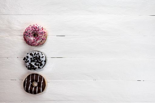 The colorful glazed donuts with sprinkles on wooden table