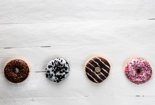 The colorful glazed donuts with sprinkles on wooden table