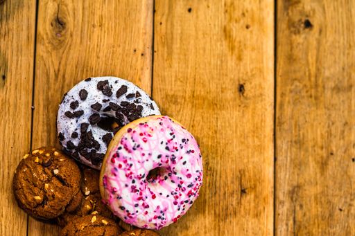 A top view of colorful glazed donuts with cookies on a wooden table