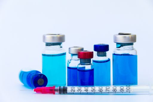 close up group of vaccine vials and syringe