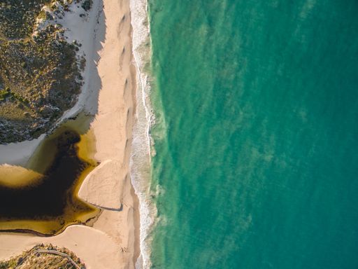 An aerial shot of the shore surrounded by the sea under the sunlight at daytime - cool for wallpapers