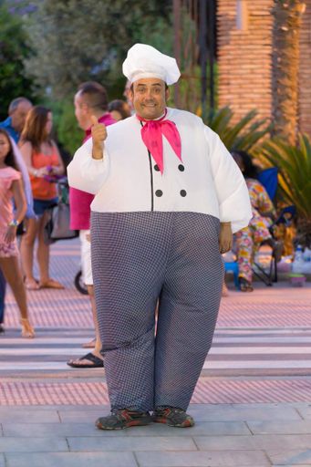 A cheerful and friendly man dressed as a cook on the street invites people to the restaurant