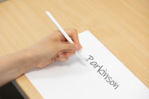 A woman with Parkinson’s disease trying to write on white paper with tremors