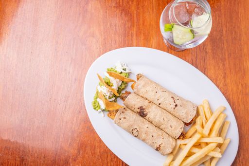 A top view of a plate with rolls and french fries with a glass of cucumber cocktail
