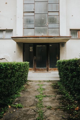 A vertical shot of an alley going to the old, abandoned building with wooden doors