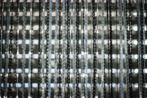 Abstract close-up of hanging chains with blurred lights in the background, creating a dynamic pattern.