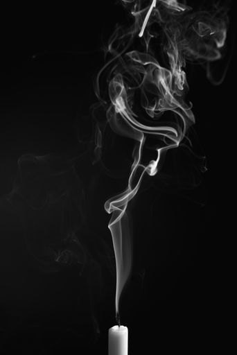 A vertical shot of the smoke of an extinguished candle isolated on a black background