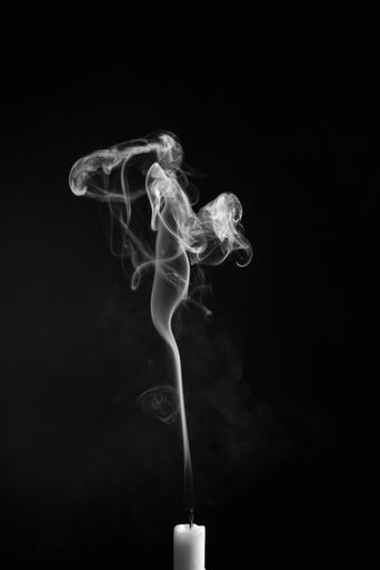 A vertical shot of the smoke of an extinguished candle isolated on a black background