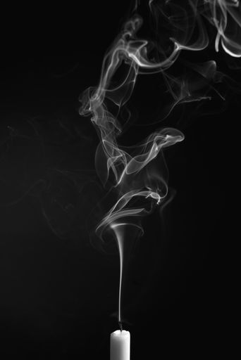 A vertical shot of the smoke of an extinguished candle isolated on a black background