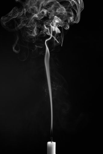 A vertical shot of the smoke of an extinguished candle isolated on a black background