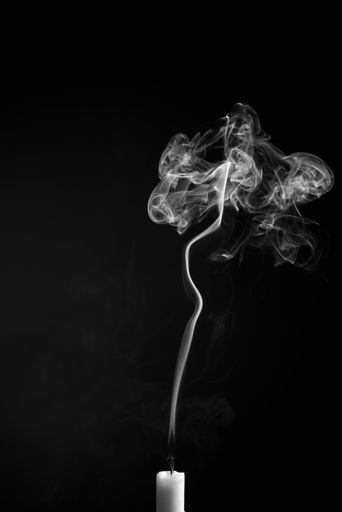 A vertical shot of the smoke of an extinguished candle isolated on a black background