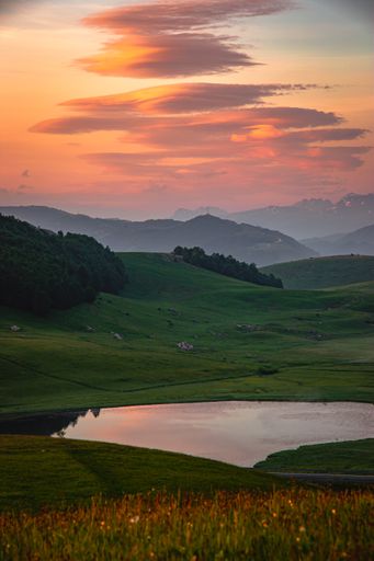 A vertical shot of hills covered in greenery under the sunlight during a beautiful sunset