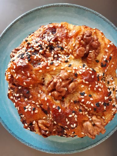 A vertical overhead shot of a freshly baked biscuit with walnuts on top in a blue plate
