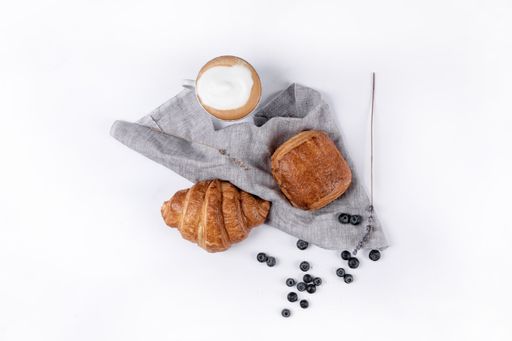 A top view of a chocolatine, a croissant, and some blueberries isolated on a white background