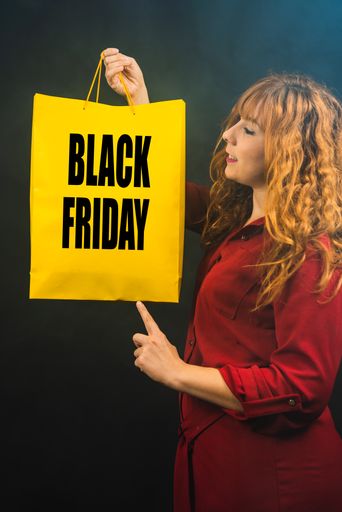 A Caucasian woman with a Black Friday shopping bag on a black background