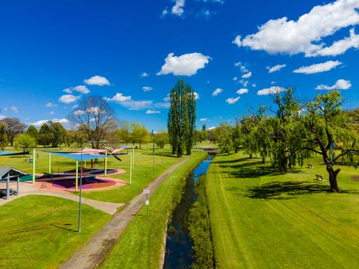 An aerial view of a beautiful green park with a narrow river in Armidale, Australia