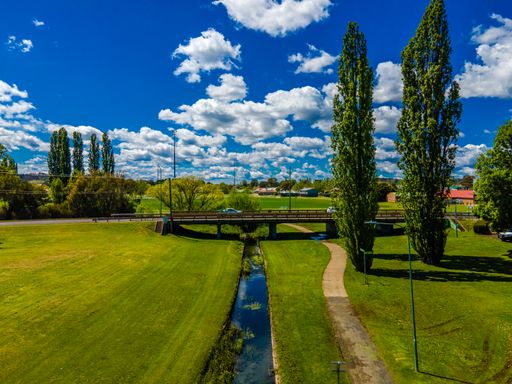 An aerial view of a beautiful green park with a narrow river in Armidale, Australia