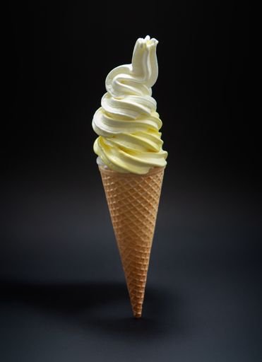 A vertical shot of soft vanilla ice cream in a cone
