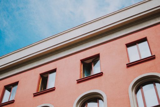 A low angle closeup shot of a pink building with windows