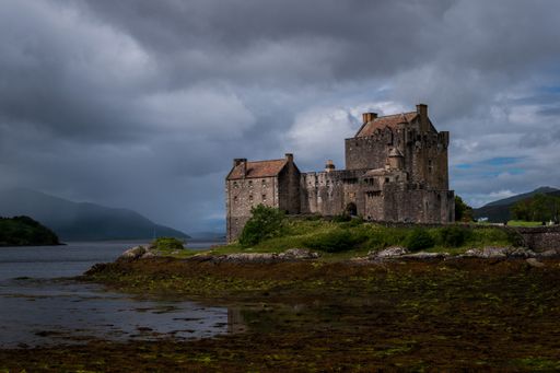 A scenic shot of the Eilean Donan Castle surrounded by a lake in UK under the cloudy sky