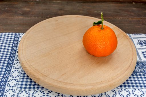 A closeup shot of a juicy tangerine on the wooden stand in the kitchen