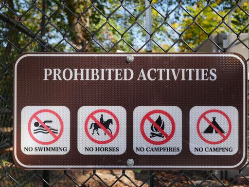 A closeup shot of prohibited activities sign attached to a fence