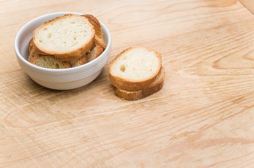 organic fresh sliced bread in a white bowl on a wooden tabletop with copy space