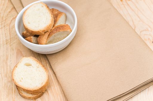 organic fresh sliced bread in a white bowl on a wooden tabletop with copy space