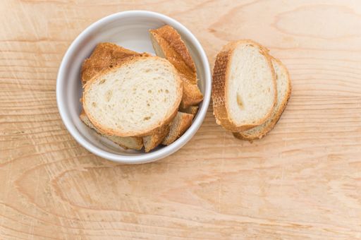 organic fresh sliced bread in a white bowl on a wooden tabletop with copy space