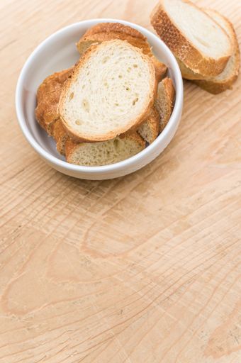 organic fresh sliced bread in a white bowl on a wooden tabletop with copy space