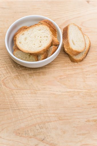 organic fresh sliced bread in a white bowl on a wooden tabletop with copy space