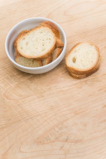 organic fresh sliced bread in a white bowl on a wooden tabletop with copy space