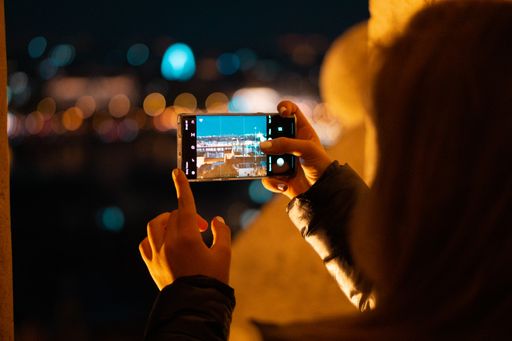A shallow focus shot of female taking pictures of the city with her mobile in Budapest