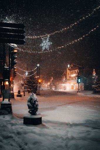 A vertical shot of a town decorated with Christmas ornaments covered in the snow at night