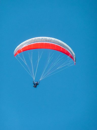 A vertical shot of a parachutist on the blue sky background