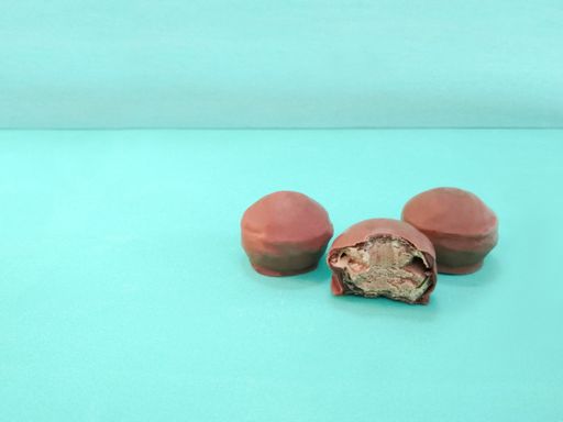 Three fresh filled chocolate pralines isolated on turquoise background with a copy space