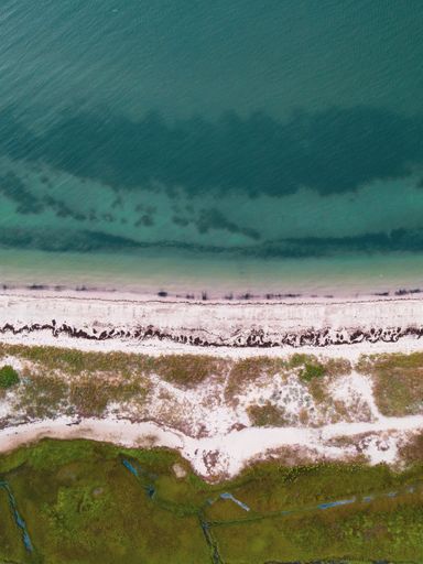A bird's eye view of a sandy shore with lagoon water