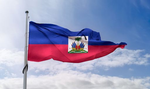 A Haiti flag waving on a pole in a blue sky