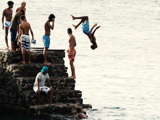 A group of young people jumping into the sea from the Fort of Santa Maria pier in Salvador, Brazil