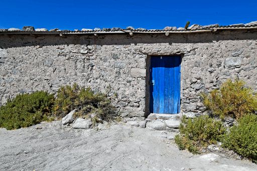 An old barn of a house with a painted blue wooden door in the northern part of Chile