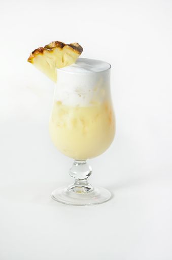 A vertical shot of a refreshing pineapple cocktail in a glass on a white background