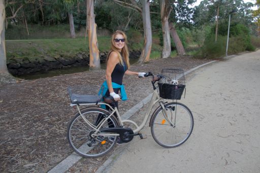 A scenic shot of a beautiful Caucasian woman wearing sunglasses and holding a bike in Spain