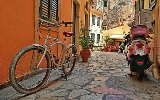 A beautiful shot of a bicycle and a moped in a narrow street of Corfu, Greece