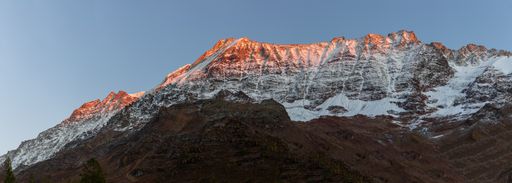 Panoramic view of Alpglow orange sunset light on snow mountain range in Valais loetschental switzerland. Lonzahoerner, Breithorn and Breitlauwihorn.