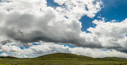 A beautiful shot of a field and a cloudy dramatic sky in the daytime.