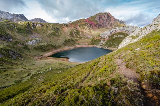 The green mountains surrounding the lake with the cloudy sky in the background