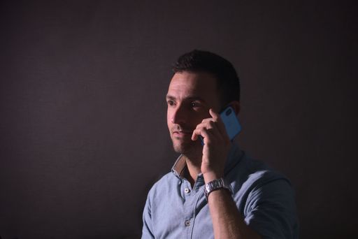 A portrait of a stubble Caucasian businessman in dark background talking on phone